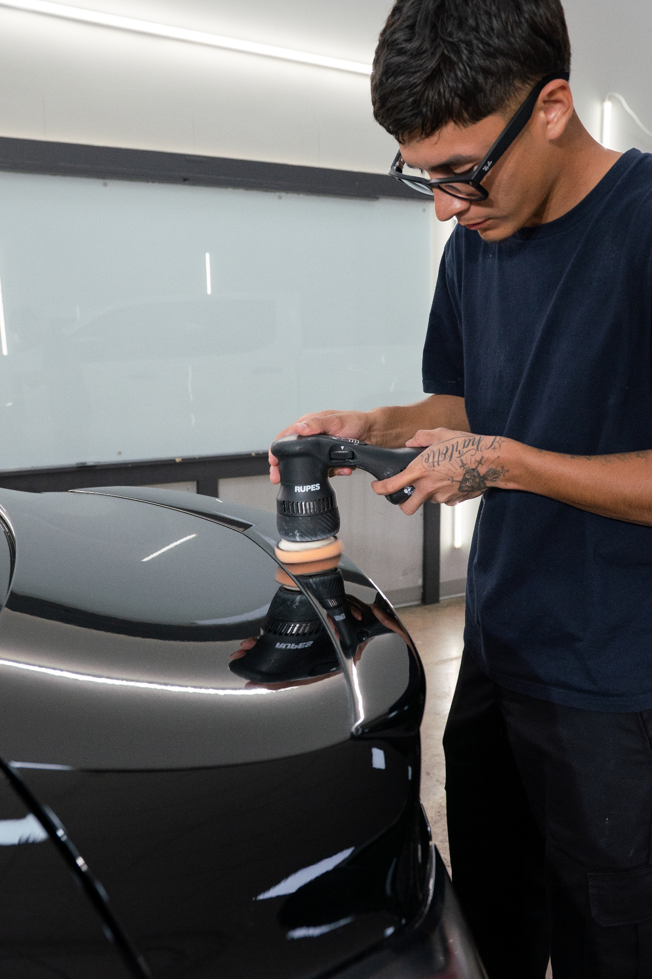 Polishing a black Porsche fender with a RUPES polisher