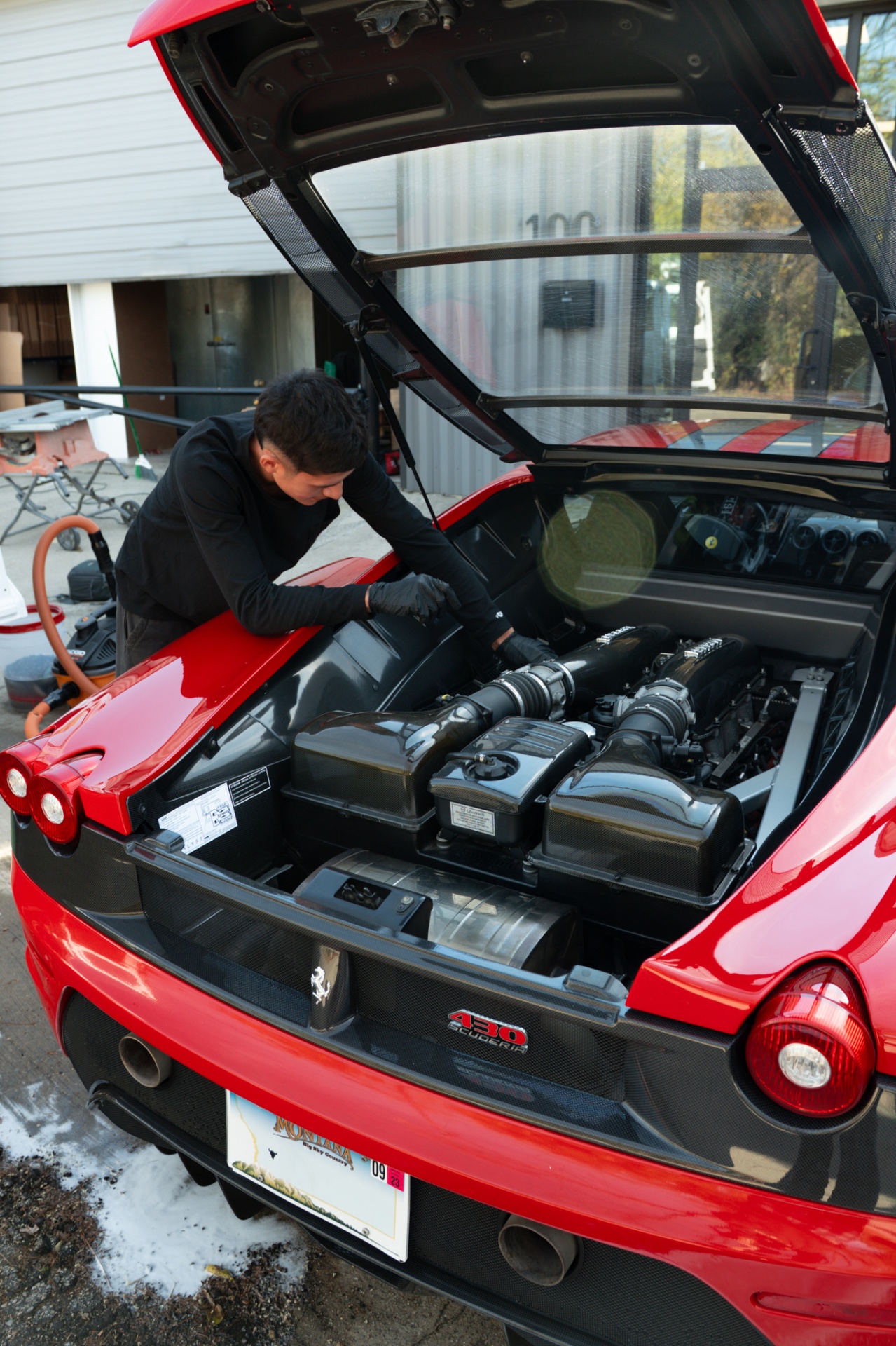 Detailer carefully cleaning the engine bay of a red Ferrari